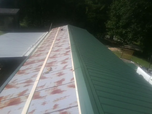 Old rusted panels beside newly installed green metal roofing — Wind Damage Roof Repair by Roofing Brothers in Meridian