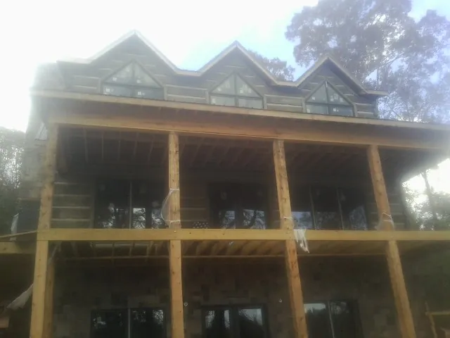 Dormers and porch framing on a large log home under construction — Roof Coating work by our crew in Meridian
