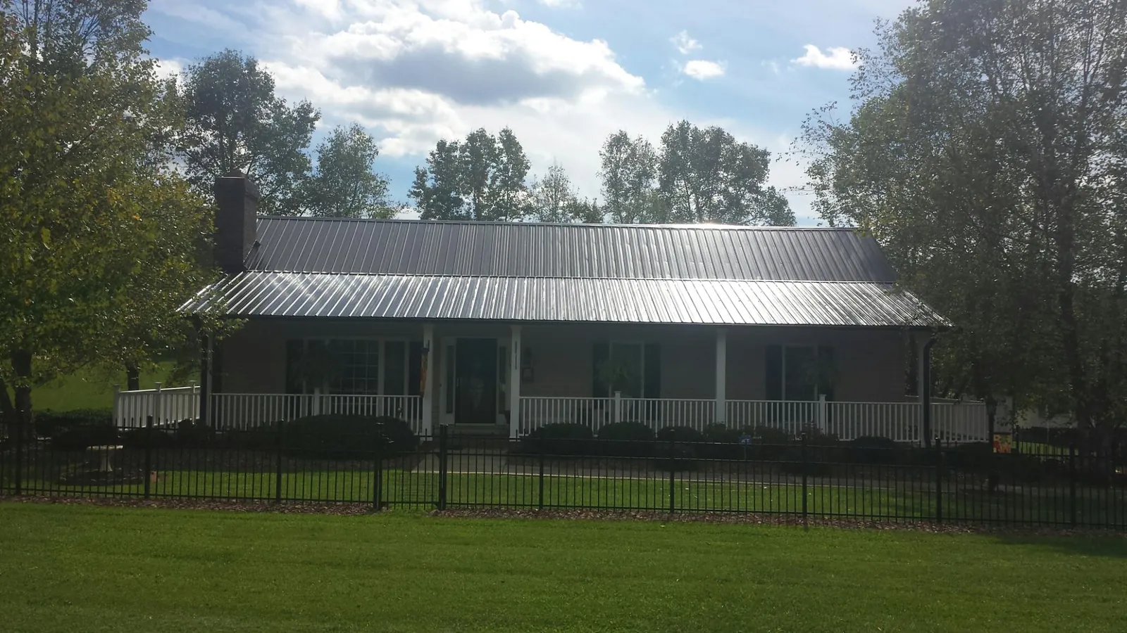 Gray metal roof on a brick ranch with a full width front porch — Gutter Guard Installation work by our crew in Meridian